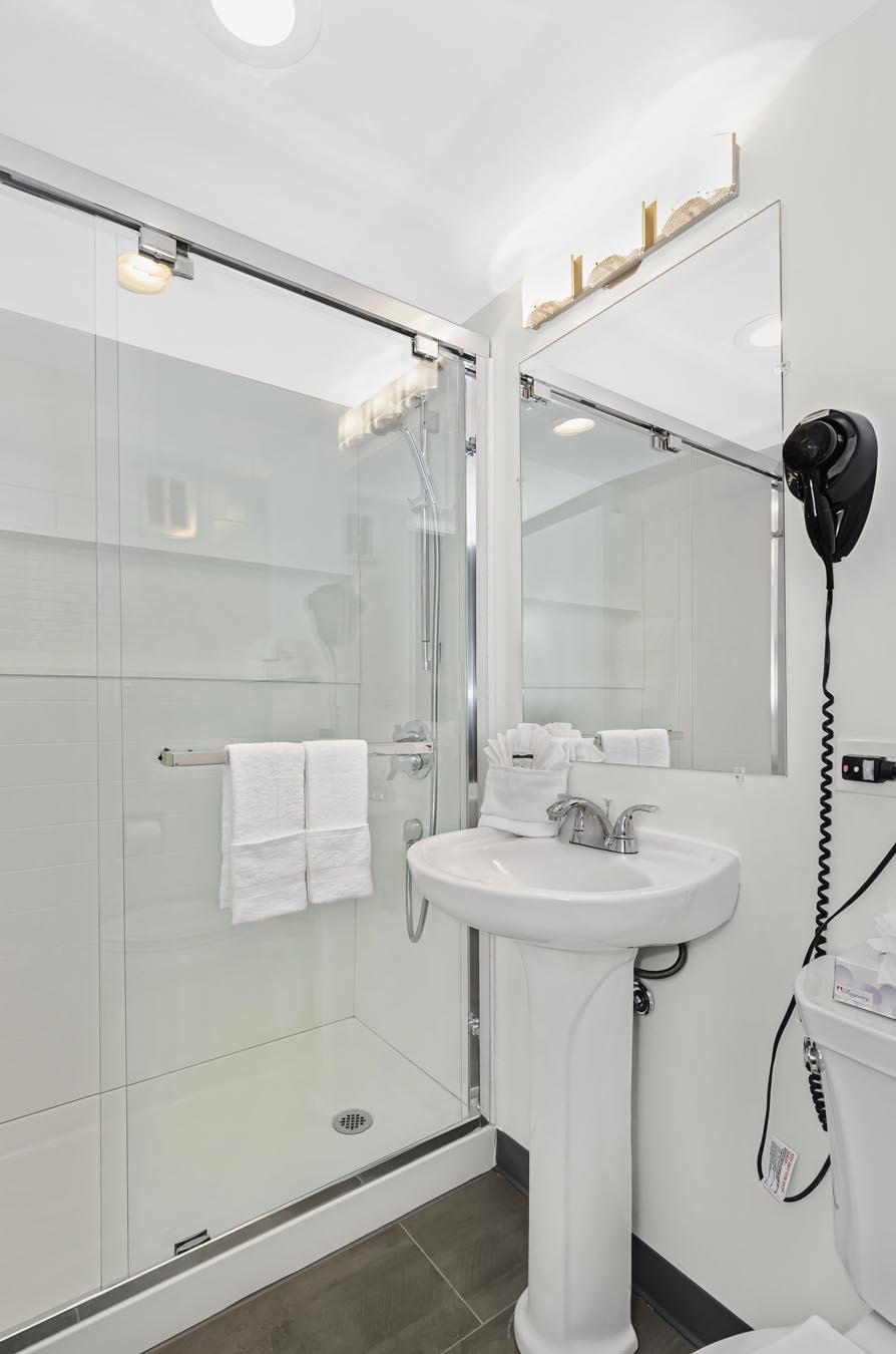 Shower beside white vanity and mirror