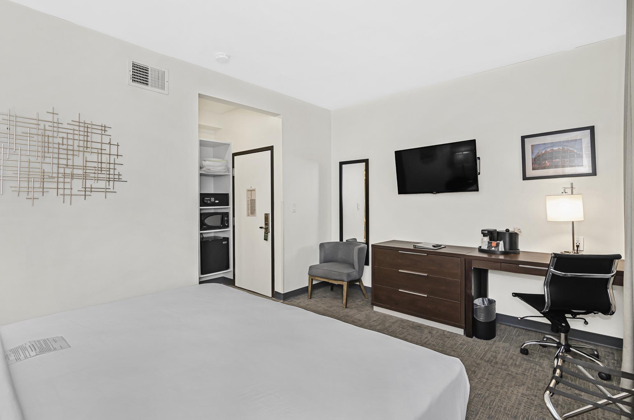 Brown desk, swivel chair, mounted TV, and king bed