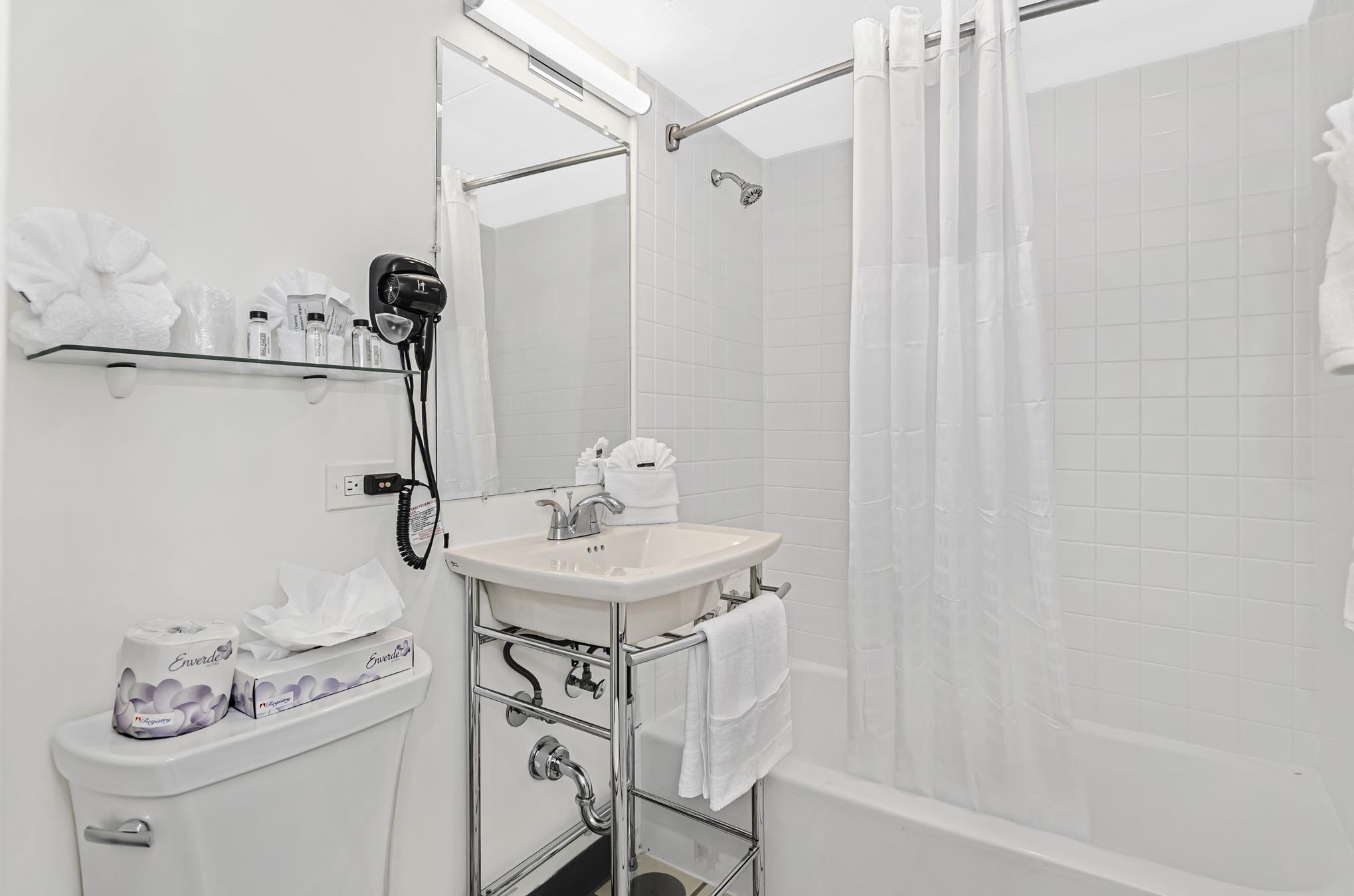 Bathtub with shower curtain and vanity beside toilet