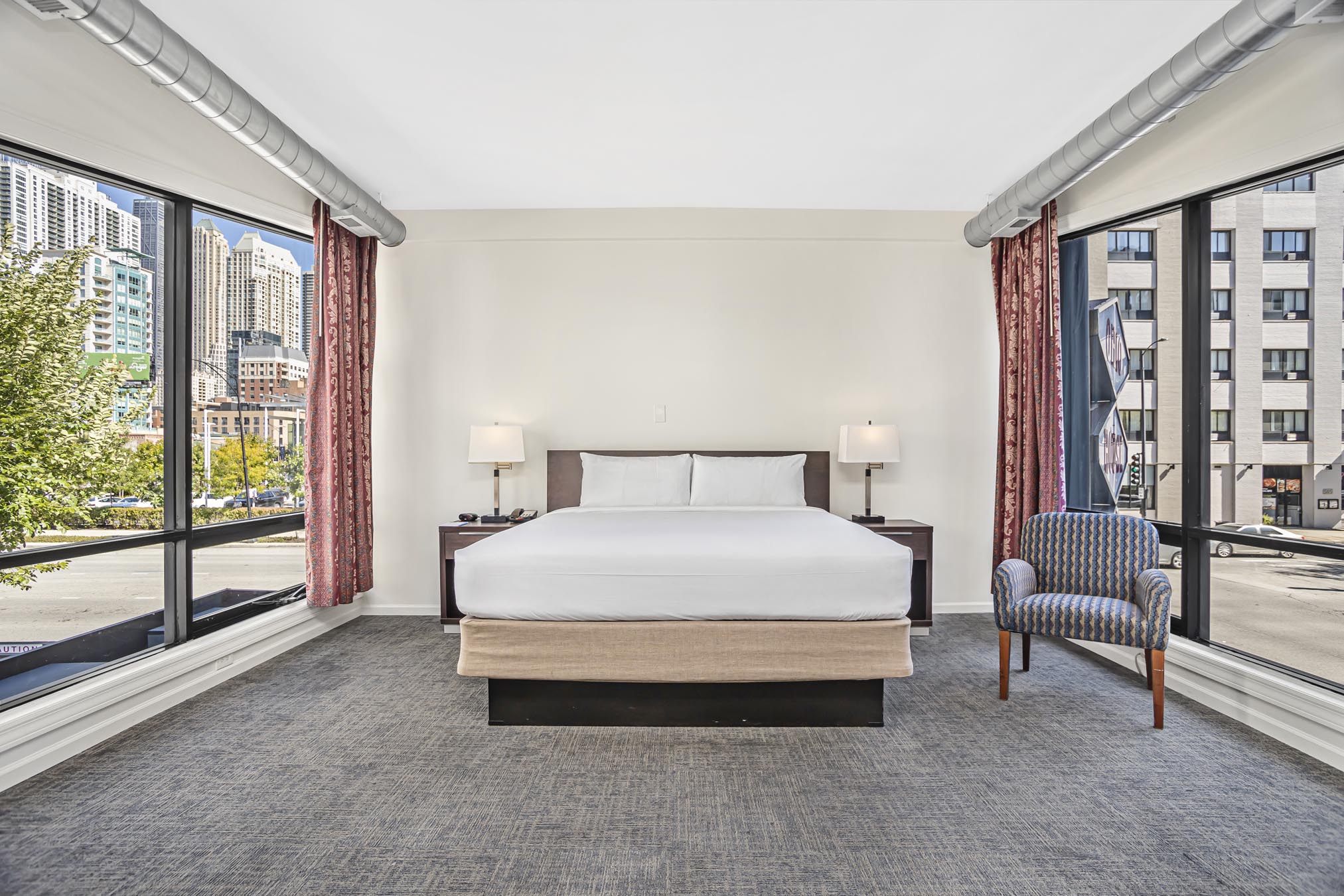 King bed, grey chair, and large windows on both sides of room