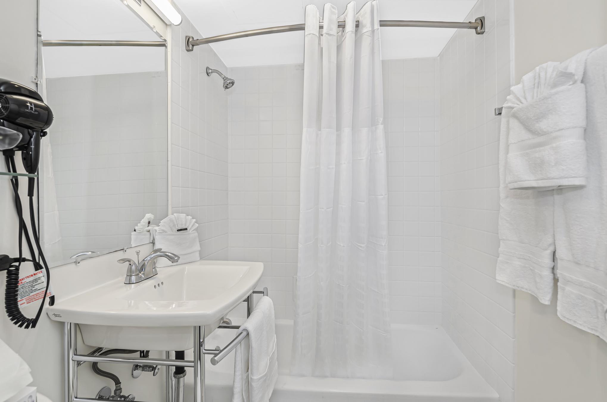 Shower with curtain beside vanity