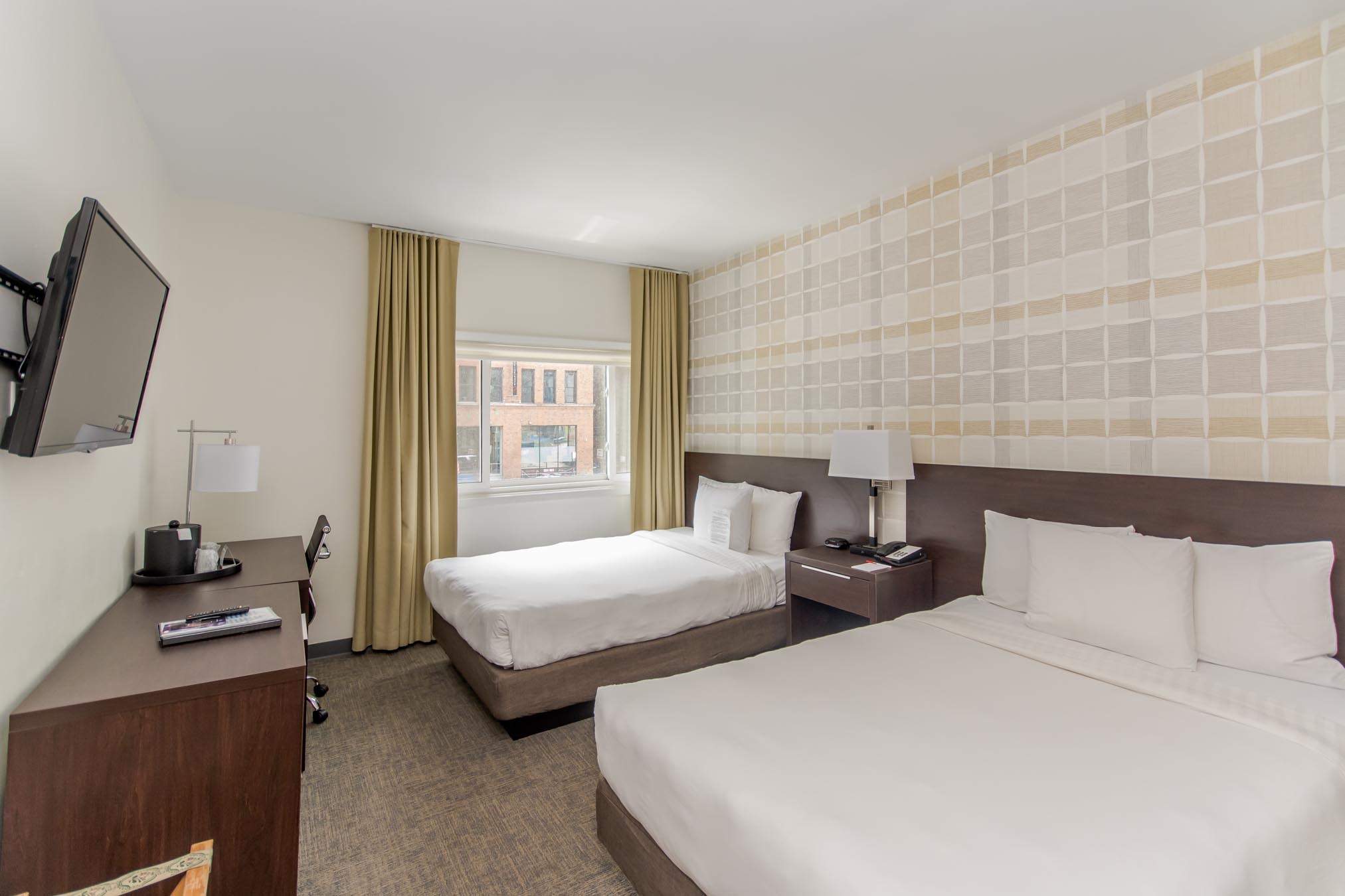 Mounted TV, two double beds, side tables, desk, and chair